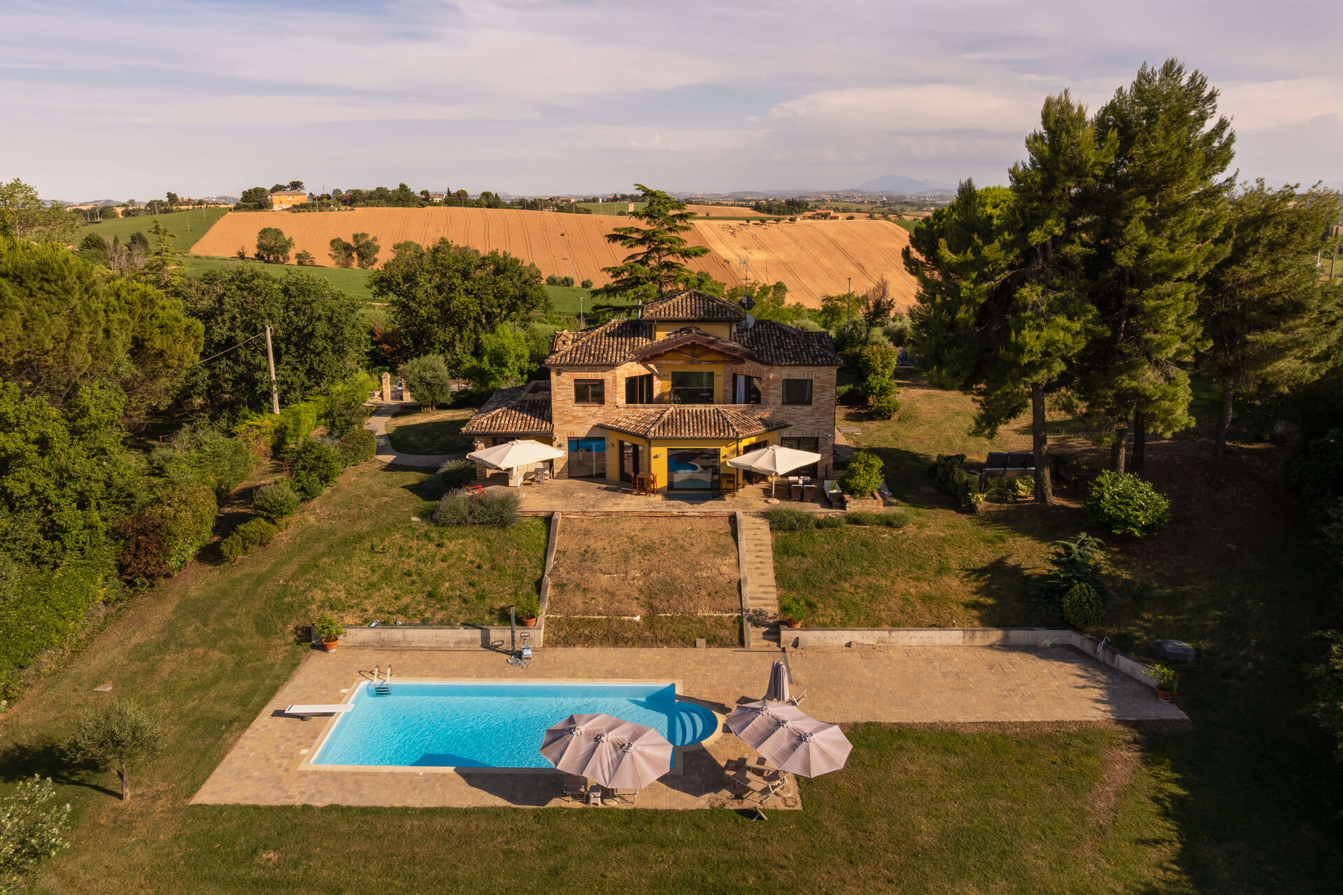 Vista aerea della villa con piscina tra i campi dorati